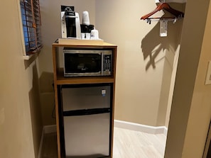 Une petite cuisine équipée d’un four à micro-ondes, d’une machine à café et d’un petit réfrigérateur.