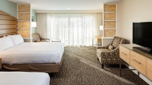 Una habitación de hotel con una cama grande, un escritorio, un televisor y un sillón estampado.