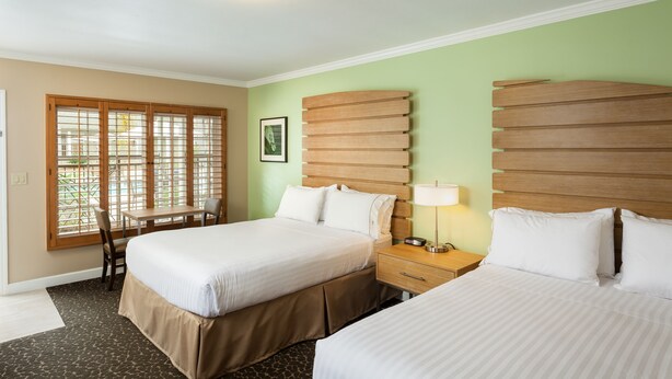 Habitación de hotel con dos camas, un escritorio y una silla.