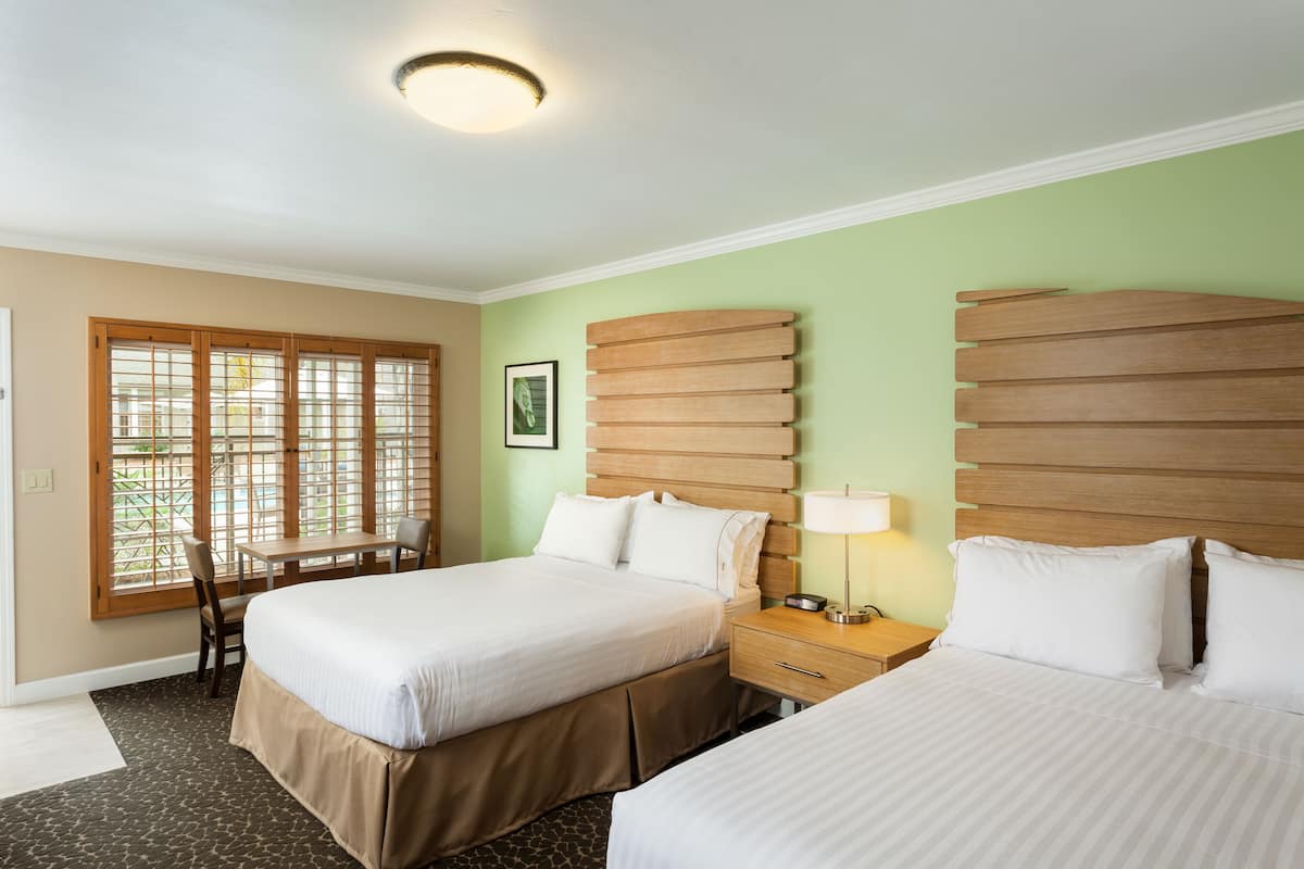 Habitación de hotel con dos camas, un escritorio y una silla.