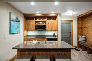 A kitchen with wooden cabinets, a granite countertop, a stainless steel refrigerator, and a microwave.
