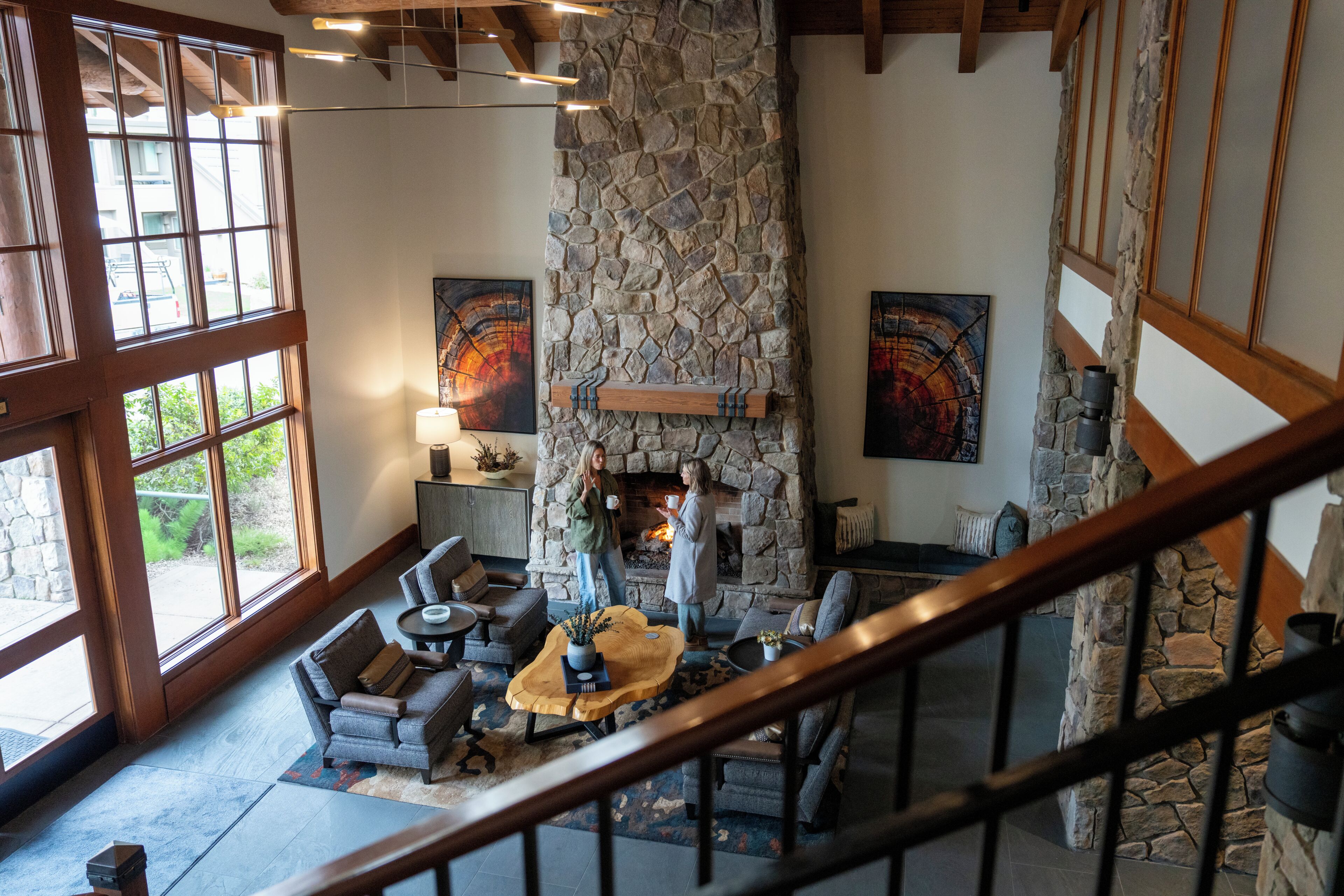 A stone fireplace, a wooden staircase, and a view of the outdoors.