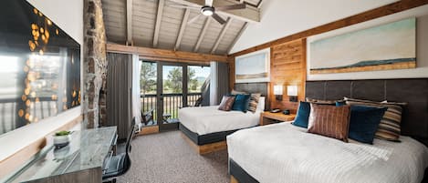 A bedroom with two beds, a desk, and a balcony with a view.