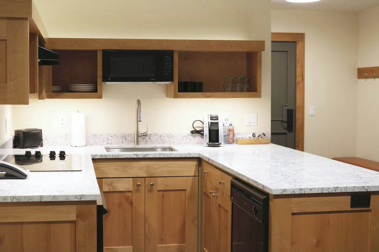A kitchen with wooden cabinets, a microwave, a coffee maker, and a dishwasher.