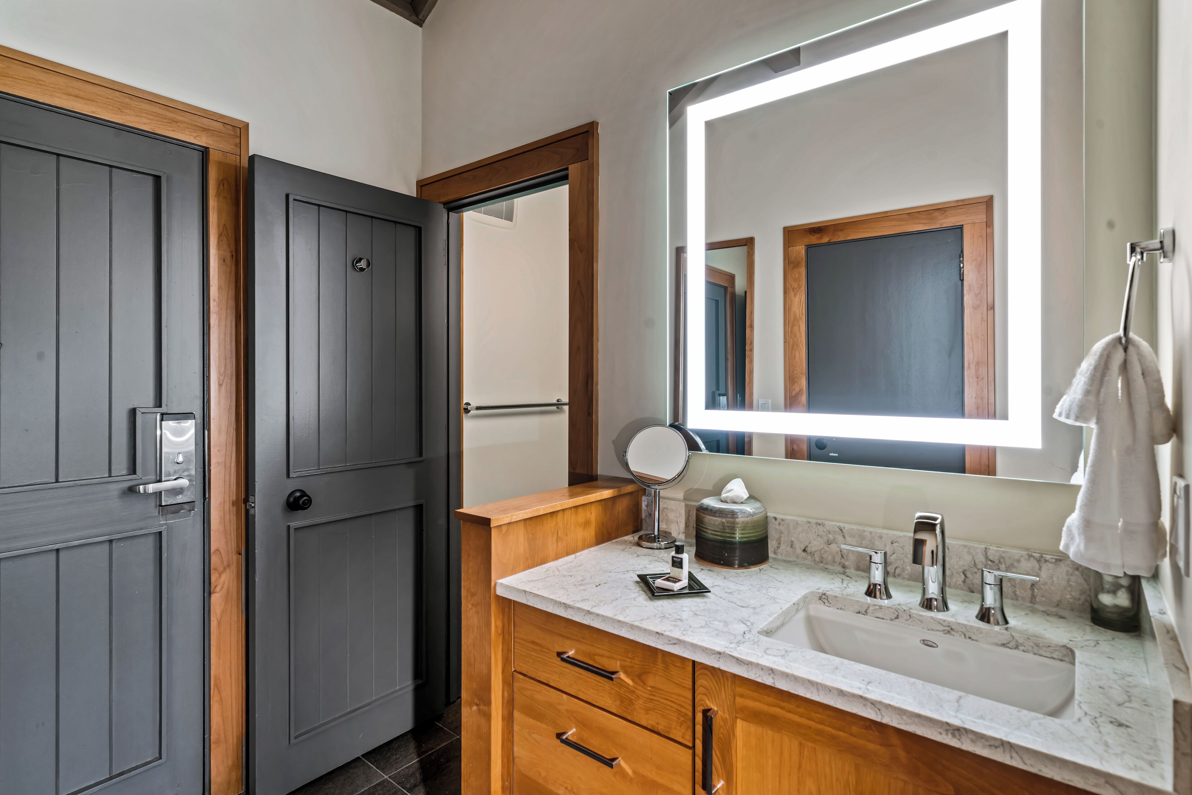 A bathroom with a large mirror, a sink, a towel rack, and wooden cabinets.