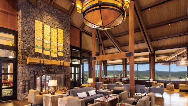 A spacious lobby with a stone fireplace, comfortable seating, and large windows offering scenic views.