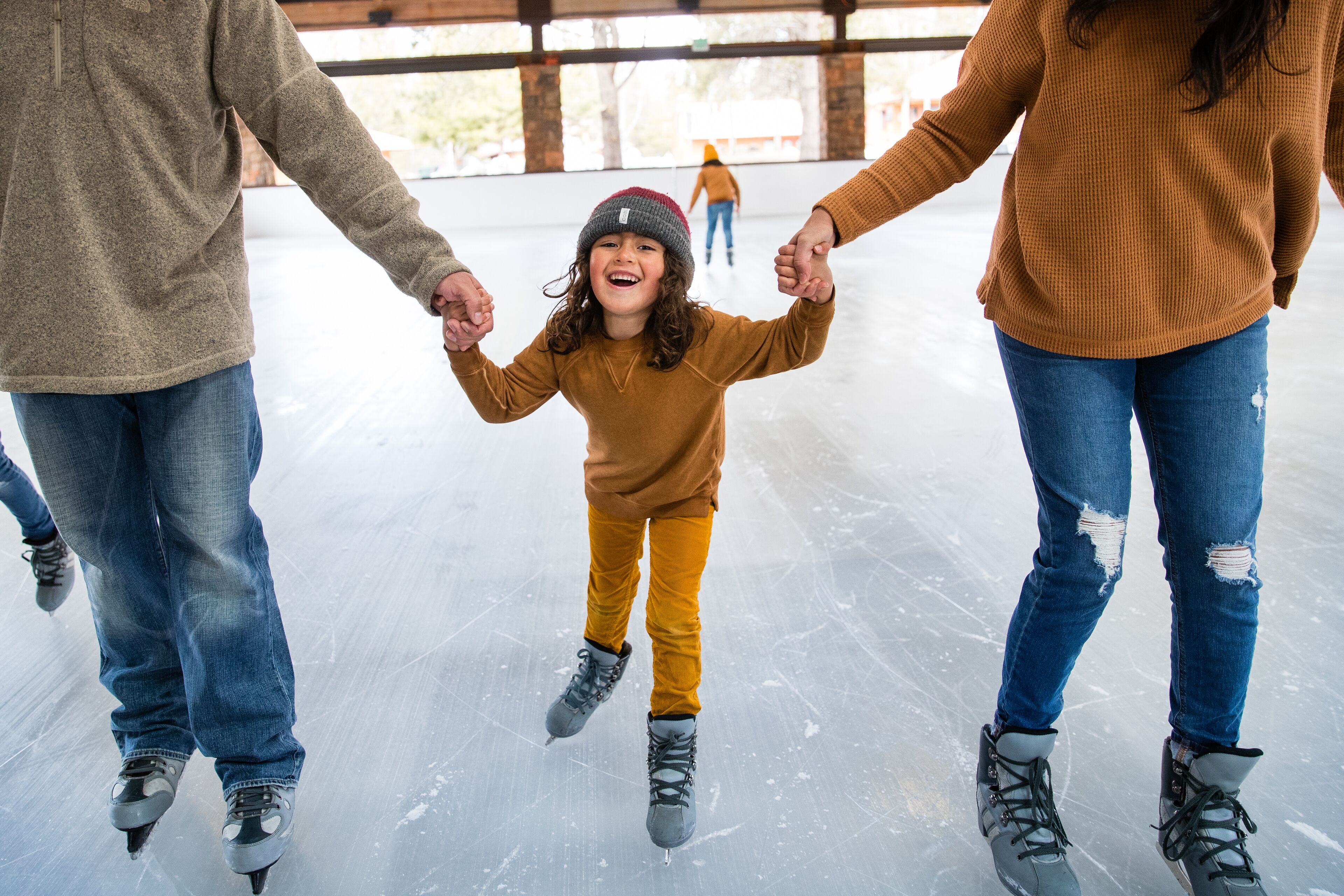 A family on an ice rink, holding hands.