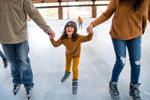 A family on an ice rink, holding hands.