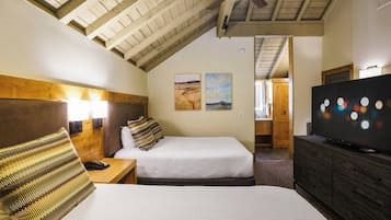 A hotel room with two beds, a television, and artwork on the walls.