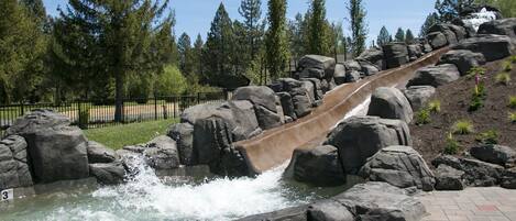 A water slide with a rocky landscape and trees in the background.