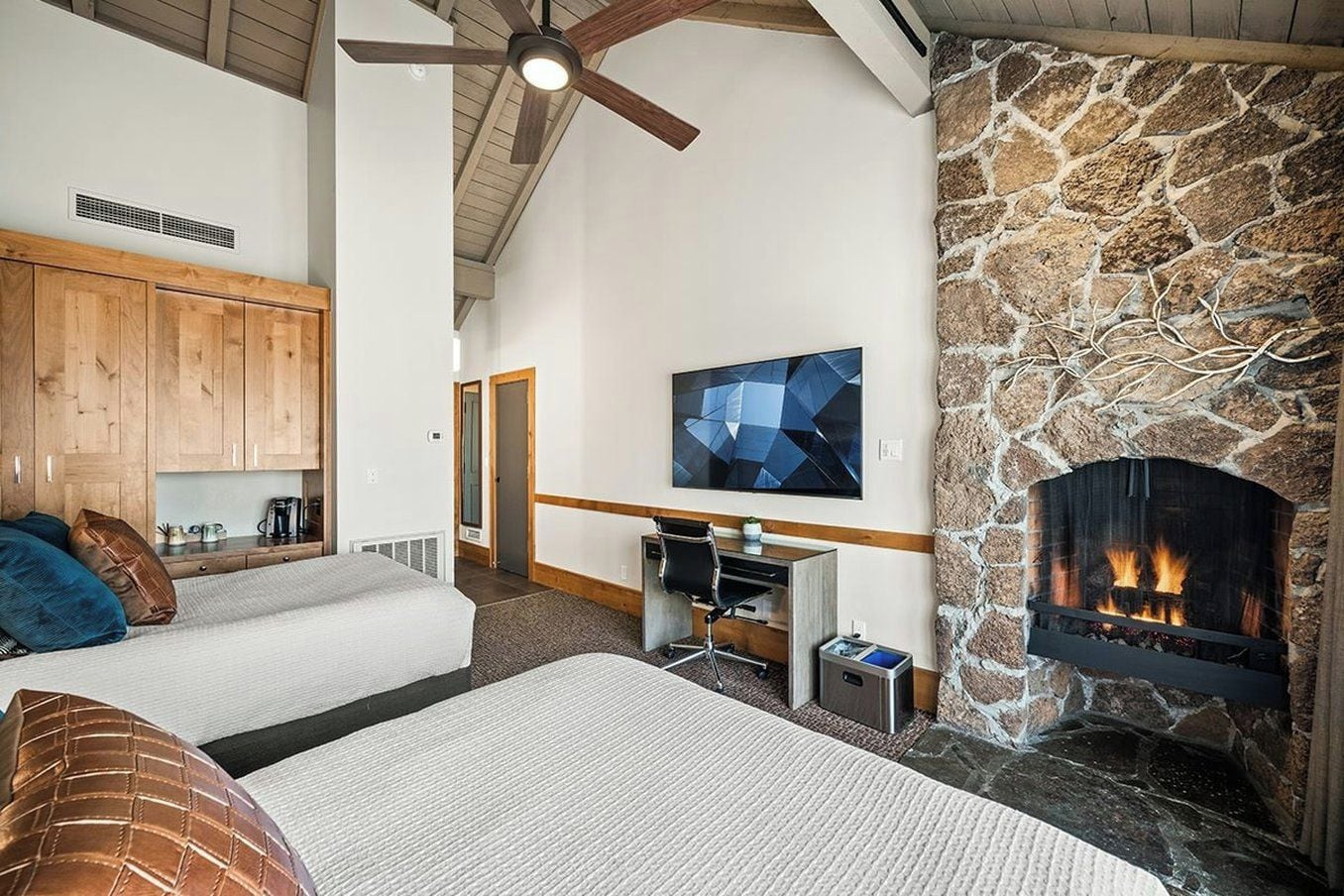 A cozy room with a fireplace, a bed, a desk, and a television.