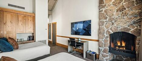 A cozy room with a fireplace, a bed, a desk, and a television.