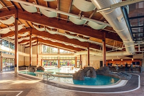 An indoor swimming pool with a waterfall feature, wooden beams, and a bar area. - Sunriver Resort (Bend)