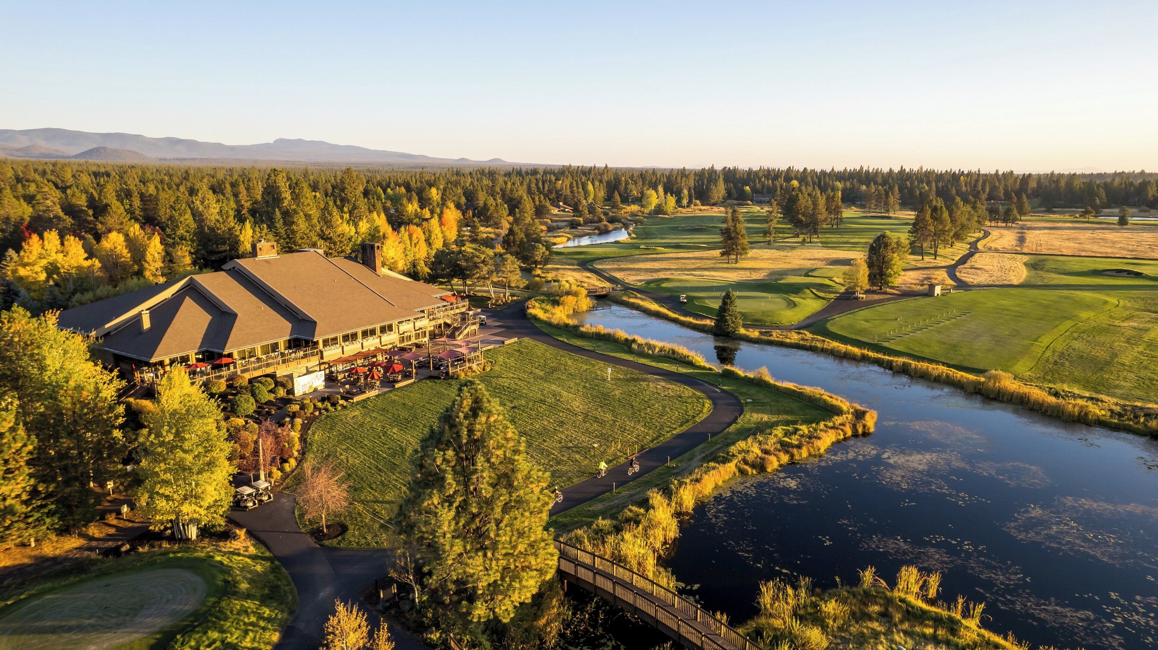 A lodge with a large building, a river, and a forested area.