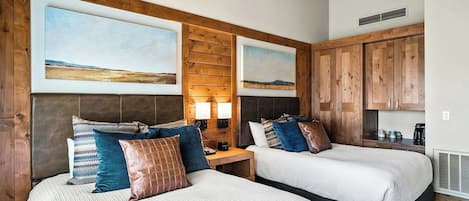 A hotel room with two beds, wooden headboards, and artwork on the walls.