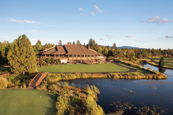 A large building with a golf course and a pond.