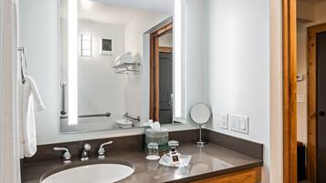 A modern bathroom with a large mirror, a sink, and a shower area visible through the doorway.