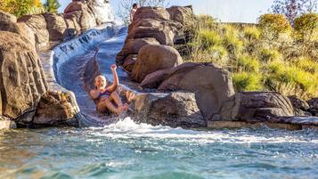 A water slide with large rocks and a person sliding down.