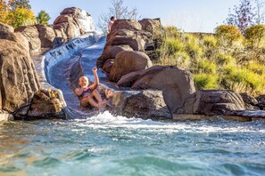 A water slide with large rocks and a person sliding down.