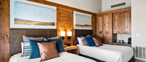 Ein Hotelzimmer mit zwei Betten, Holz-Kopfteilen und großen Landschaftsbildern.