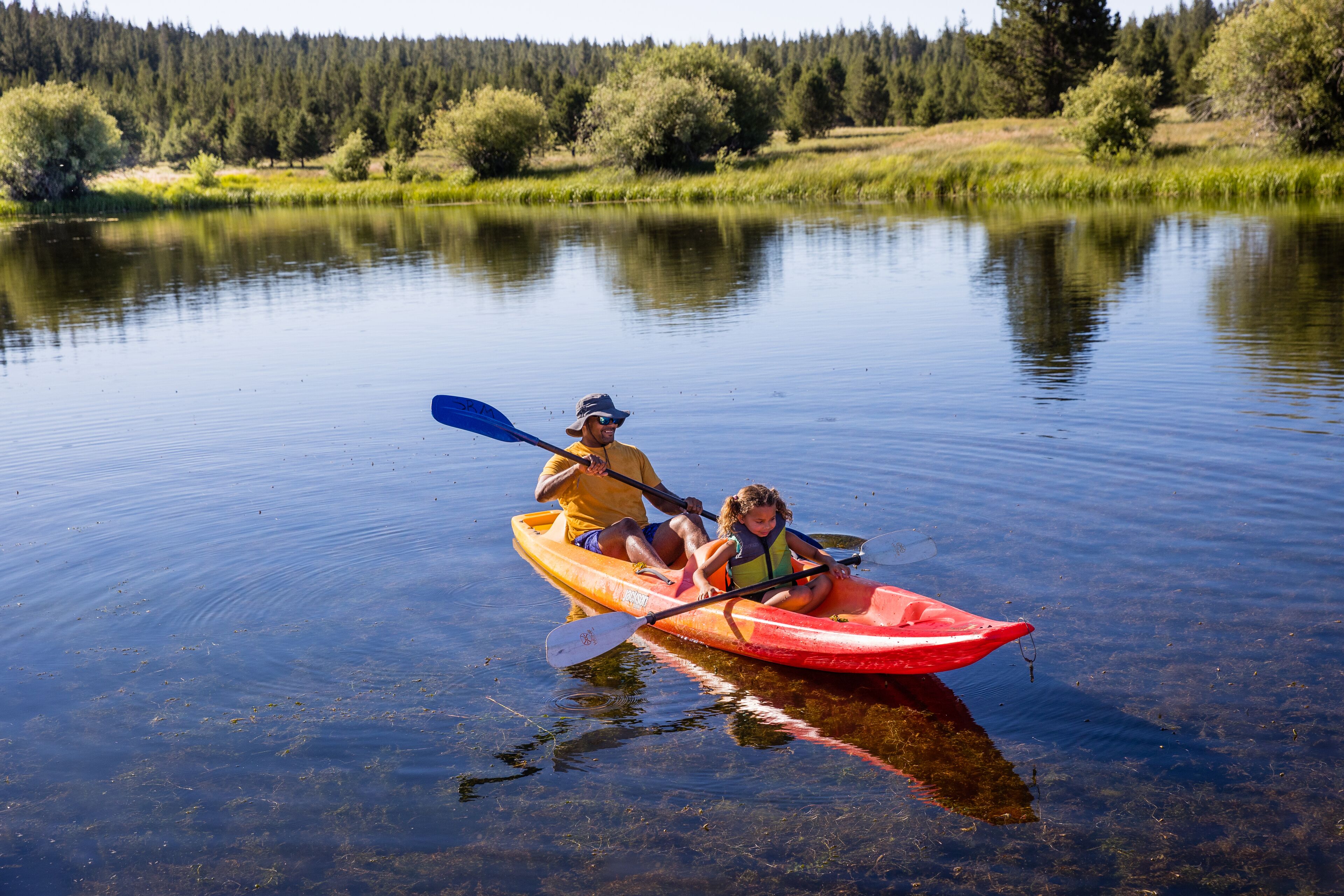 Un kayak sur une étendue d’eau calme, avec une forêt en arrière-plan.
