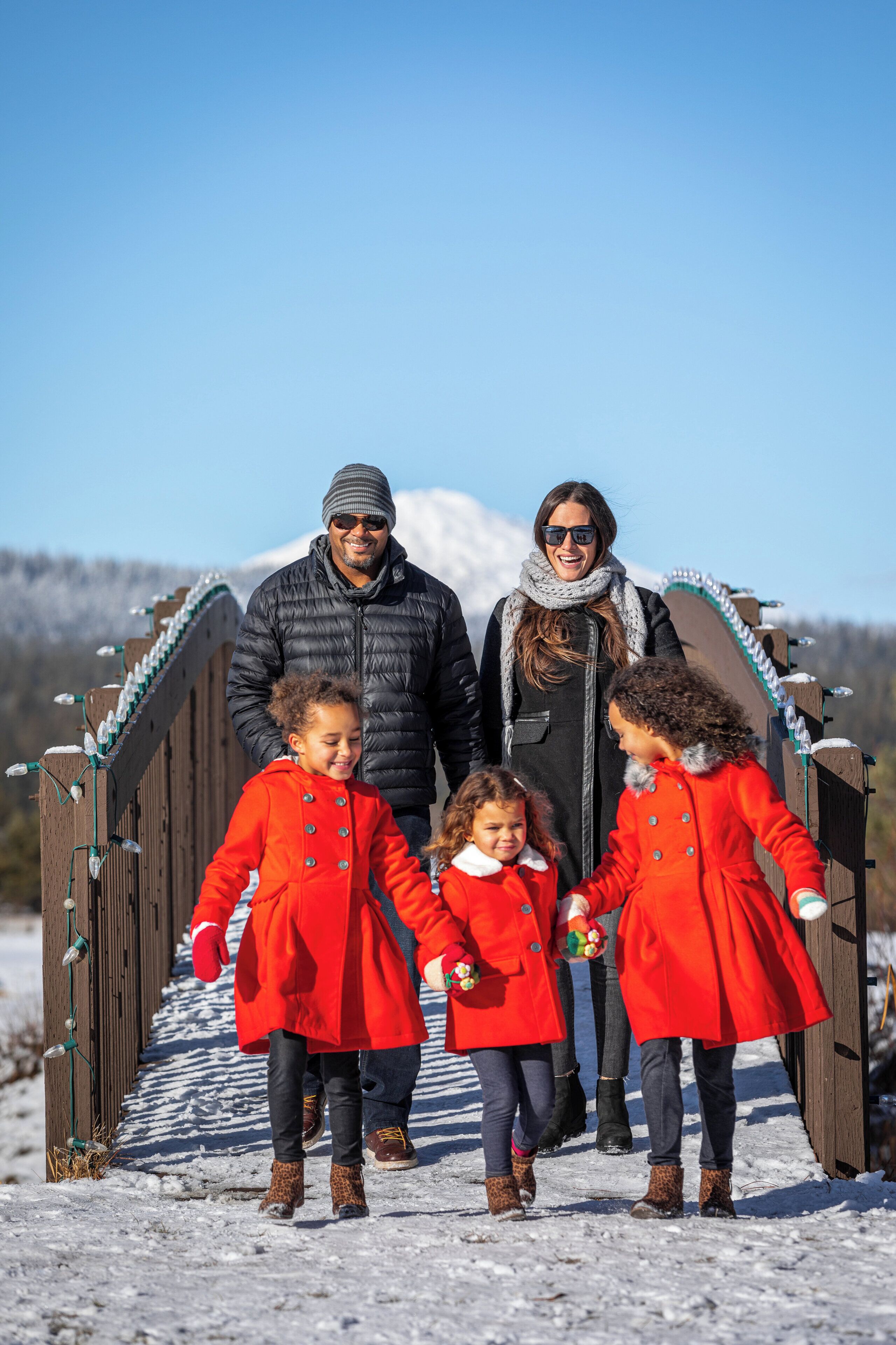 A family walking on a wooden bridge with snow on the ground.