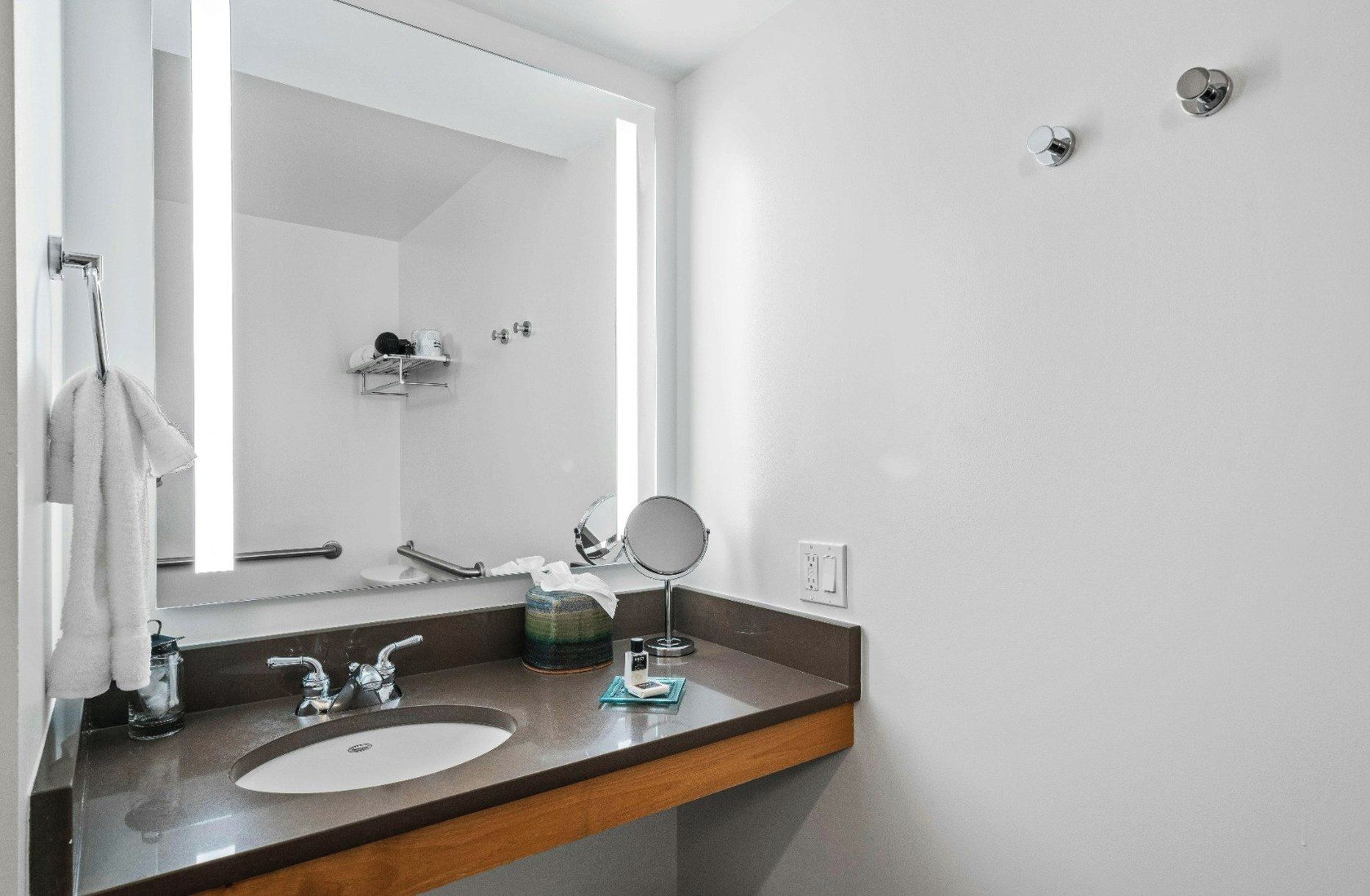 A modern bathroom with a double sink, a mirror, and a towel rack.