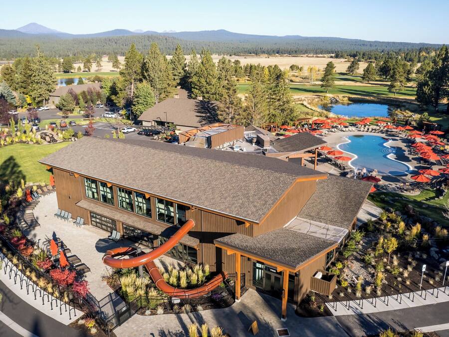 A resort with a large building, a swimming pool, and a mountain backdrop.