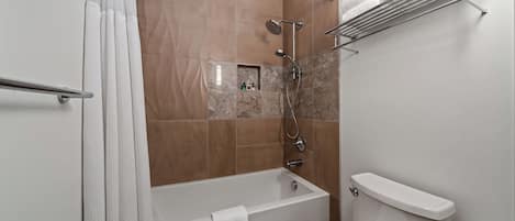 Une salle de bain avec une baignoire, une douche et des toilettes.
