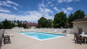 A rectangular pool with a white border, surrounded by lounge chairs and a table. - Quality Inn (Newport News)