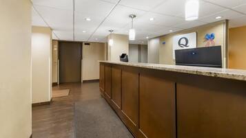 A hotel reception area with a marble counter, a reception desk, and a wall-mounted sign with a logo.