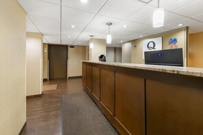 A hotel reception area with a marble counter, a reception desk, and a wall-mounted sign with a logo.