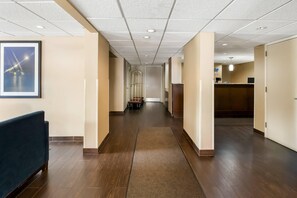 A hotel corridor with a reception desk, a seating area, and a framed picture on the wall. - Quality Inn (Newport News)