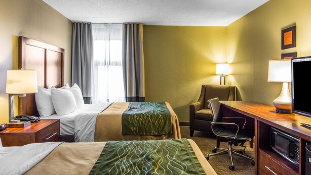 A hotel room with two beds, a desk with a computer, a chair, and a TV. - Quality Inn (Newport News)