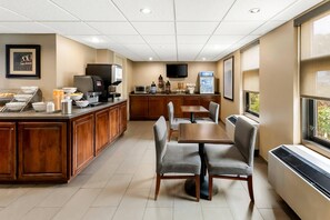 A hotel dining area with a wooden counter, buffet, and seating. - Quality Inn (Newport News)