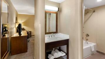 A hotel bathroom with a sink, mirror, and shower.