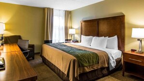 A hotel room with a large bed, a desk, two lamps, and a chair. - Quality Inn (Newport News)