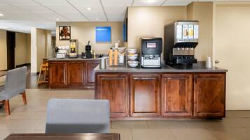 A hotel lobby with a reception desk, seating area, and a coffee machine.