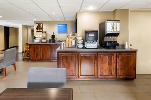 Eine Hotelhalle mit Empfangstresen, Sitzgelegenheiten und einer Kaffeemaschine.