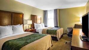 A hotel room with two beds, a desk, a television, and a window with curtains. - Quality Inn (Newport News)