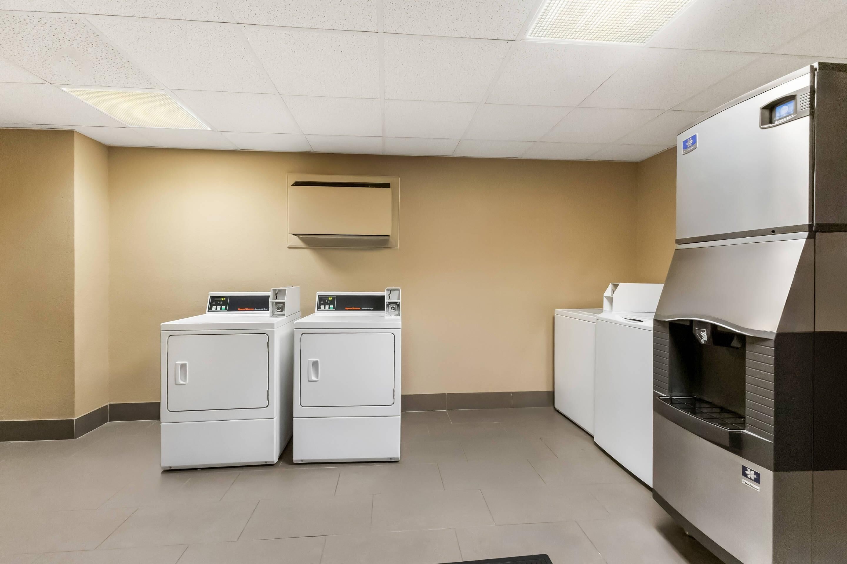 A laundry room with two front-loading washers and a stacked dryer.