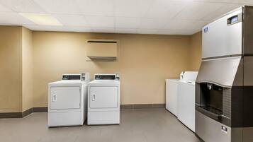 A laundry room with two front-loading washers and a stacked dryer.