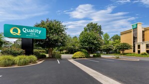 A Quality Inn by Choice Hotels with a clear sky, parking lot, and greenery. - Quality Inn (Newport News)