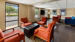 A hotel lobby with seating areas, a television, and large windows. - Quality Inn (Newport News)