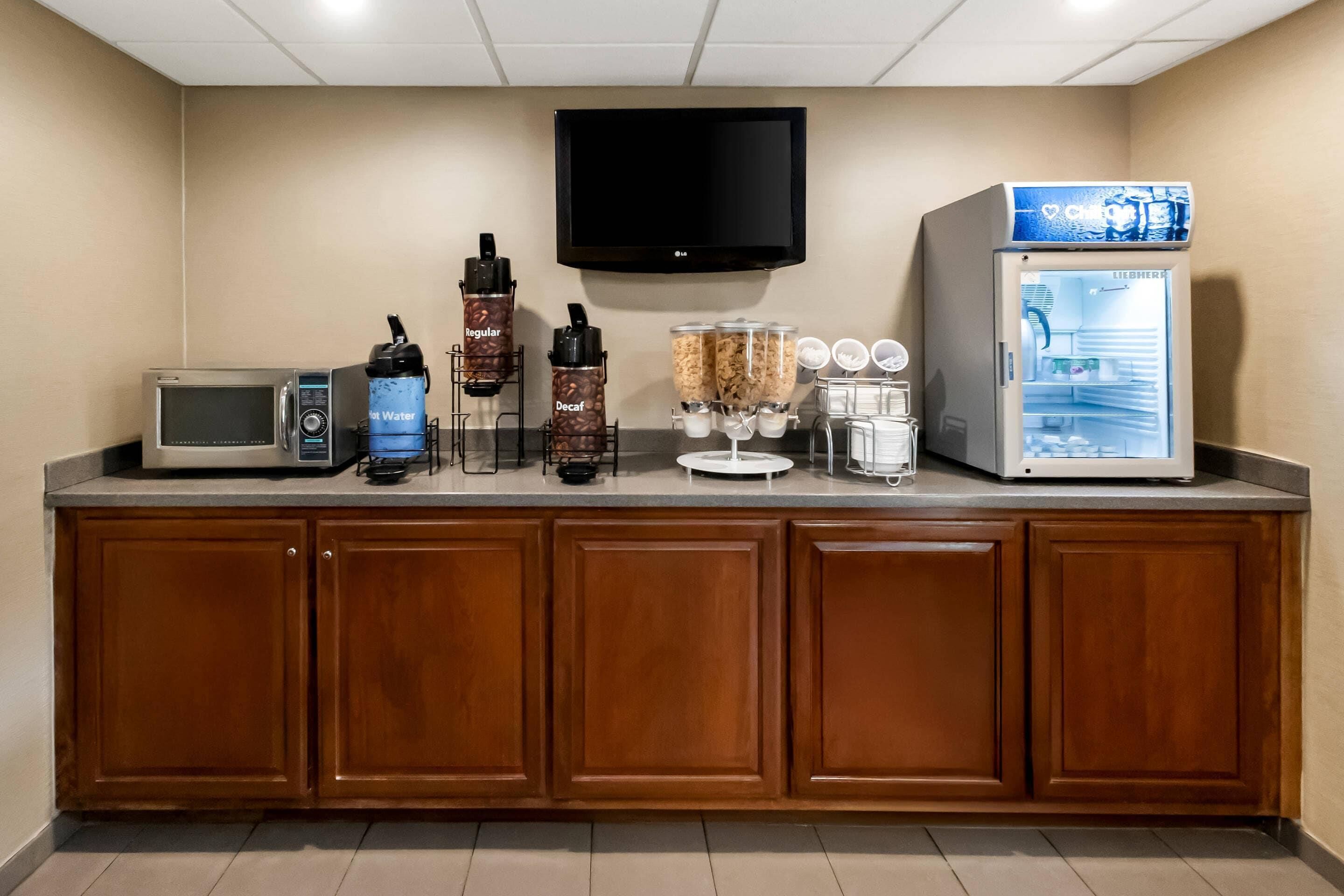 A kitchenette with a microwave, hot water dispenser, coffee machine, and a refrigerator.