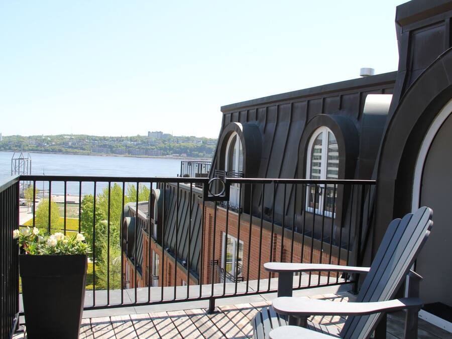 A balcony with a view of a body of water, a railing, and a seating area with a chair and table.