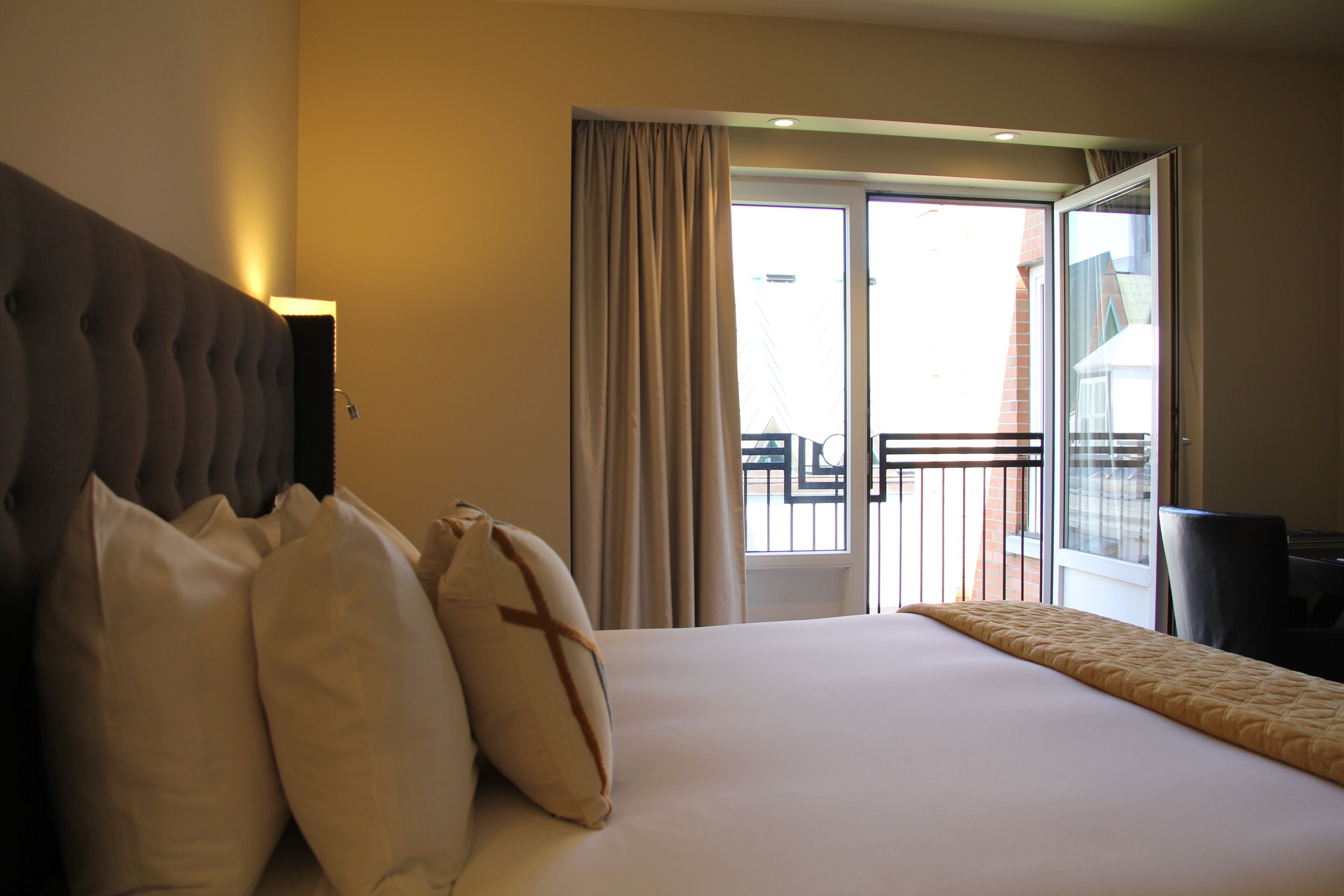 Habitació d'hotel amb un llit gran, un capçal i vistes a un balcó.