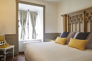 Relax in a spacious room with a large bed and comfortable chair, featuring a carved headboard and plush pillows.