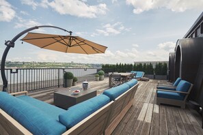 Enjoy a serene view of the water and cityscape from this outdoor deck, featuring a comfortable seating area with a bench and chairs.