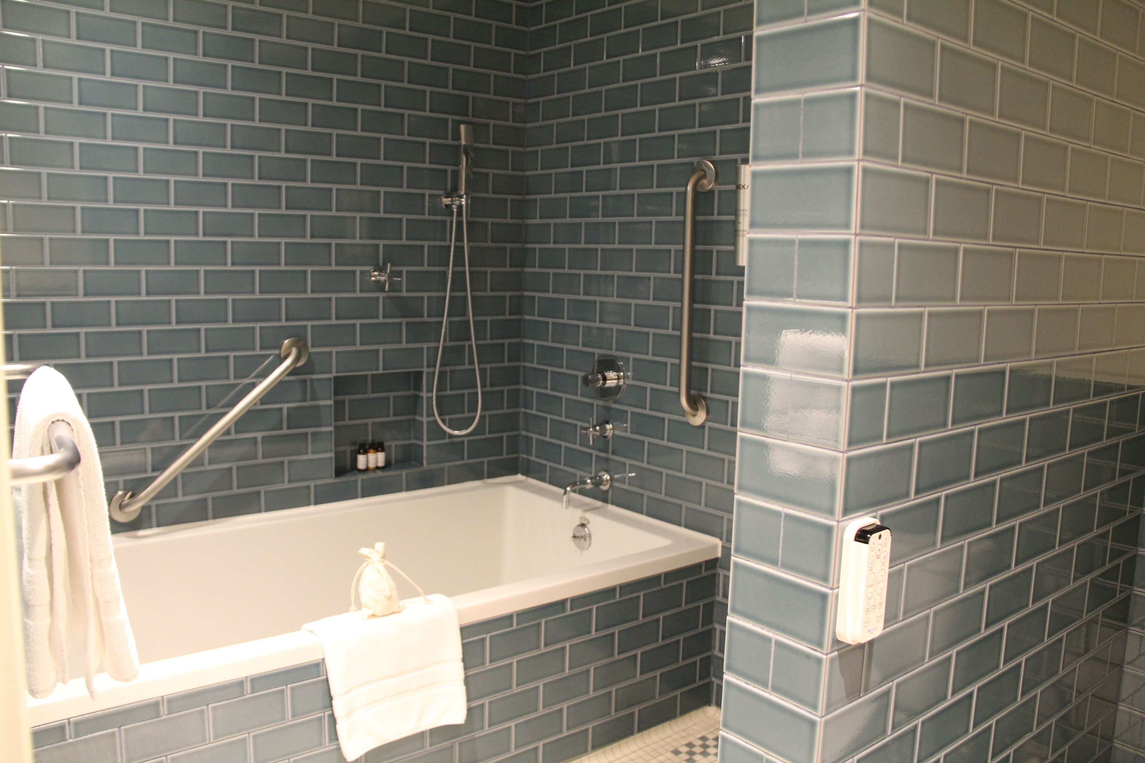 Un baño con bañera, ducha y barras de apoyo.